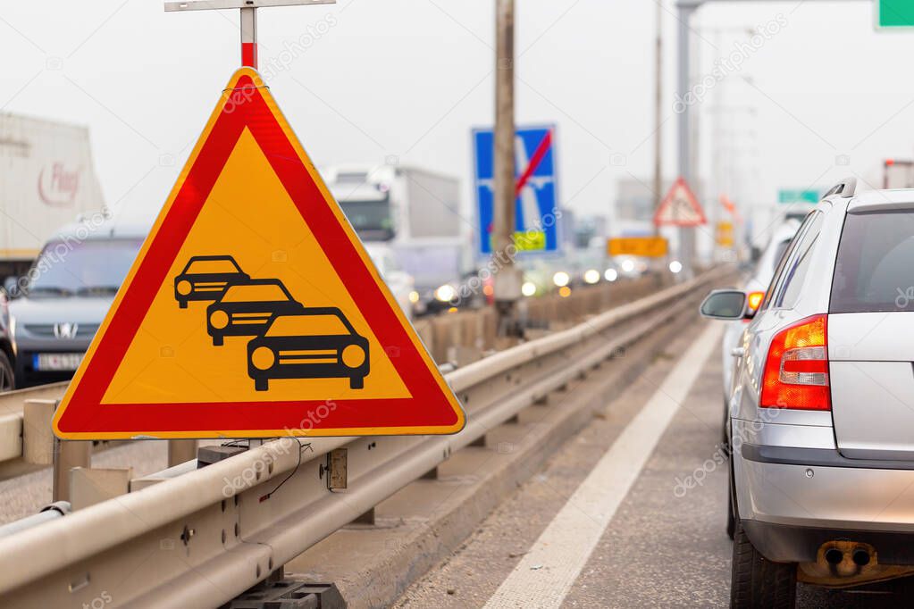 Traffic jam sign on a highway with line of cars waiting in row