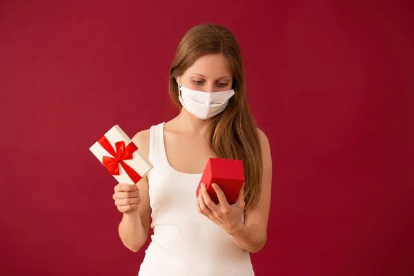 Girl with face mask opening present on valentines day — Stock Photo, Image