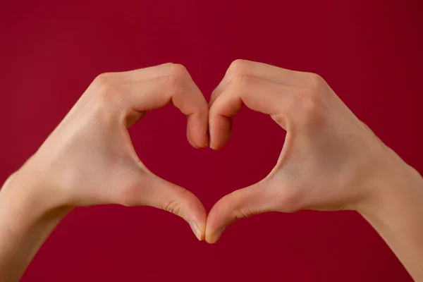 붉은 배경에 두 손으로 만든 사랑의 상징 — 스톡 사진