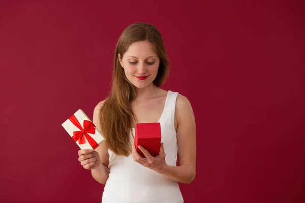 Blonde girl looking to the present on red background — 스톡 사진