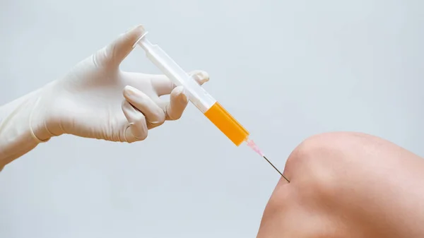 Doktor, dizinde trombosit zengini plazma enjeksiyonuyla kök hücre tedavisi yapıyor..
