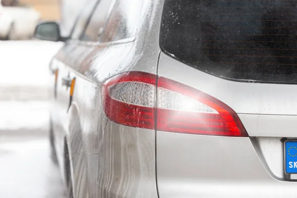 Detalhe da luz traseira de um carro moderno prata dentro carwash com sabão gotejamento. — Fotografia de Stock