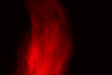 Siyah arka planda soyut kırmızı toz patlaması. Siyah arka planda soyut kırmızı toz sıçramış. Patlayan kırmızı barutun hareketsiz hareketi.