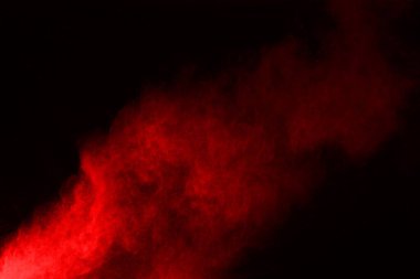 Siyah arka planda soyut kırmızı toz patlaması. Siyah arka planda soyut kırmızı toz sıçramış. Patlayan kırmızı barutun hareketsiz hareketi.