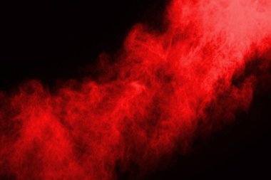 Siyah arka planda soyut kırmızı toz patlaması. Siyah arka planda soyut kırmızı toz sıçramış. Patlayan kırmızı barutun hareketsiz hareketi.