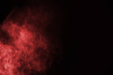 Siyah arka planda soyut kırmızı toz patlaması. Siyah arka planda soyut kırmızı toz sıçramış. Patlayan kırmızı barutun hareketsiz hareketi.