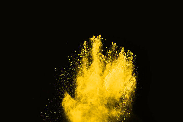 Yellow powder explosion on black background. Colored cloud. Colorful dust explode. Paint Holi.