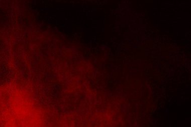 Siyah arka planda soyut kırmızı toz patlaması. Siyah arka planda soyut kırmızı toz sıçramış. Patlayan kırmızı barutun hareketsiz hareketi.