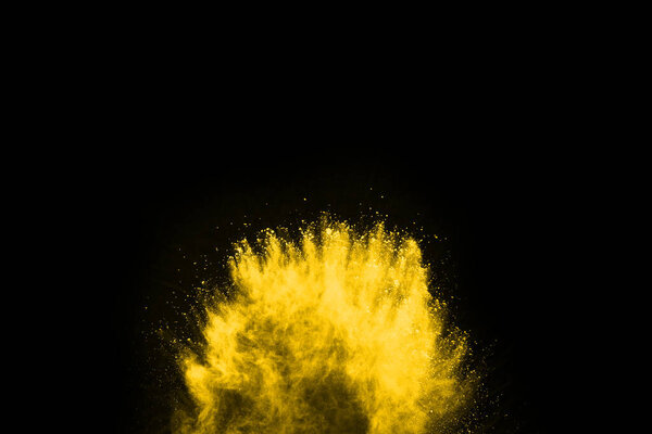 Yellow powder explosion on black background. Colored cloud. Colorful dust explode. Paint Holi.