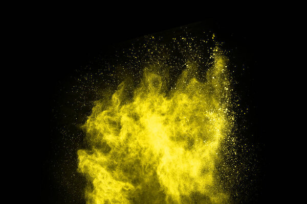 Yellow powder explosion on black background. Colored cloud. Colorful dust explode. Paint Holi.