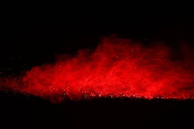 Siyah arka planda soyut kırmızı toz patlaması. Siyah arka planda soyut kırmızı toz sıçramış. Patlayan kırmızı barutun hareketsiz hareketi.