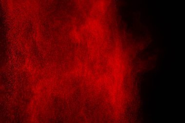 Siyah arka planda soyut kırmızı toz patlaması. Siyah arka planda soyut kırmızı toz sıçramış. Patlayan kırmızı barutun hareketsiz hareketi.