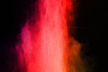 Siyah arka planda soyut kırmızı toz patlaması. Siyah arka planda soyut kırmızı toz sıçramış. Patlayan kırmızı barutun hareketsiz hareketi.