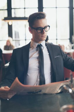 Gazete okuma gözlüğü olan takım elbiseli adam 