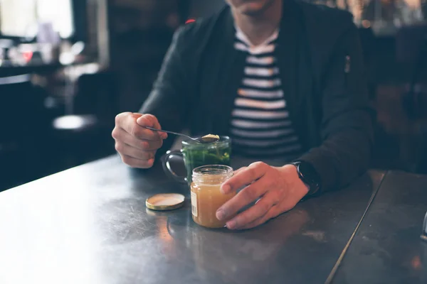 Hombre en la cafetería con cuchara tomando miel — Foto de Stock