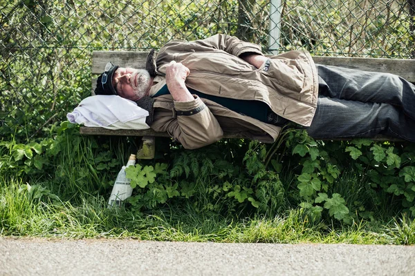 Hemlös man sova på bänken — Stockfoto