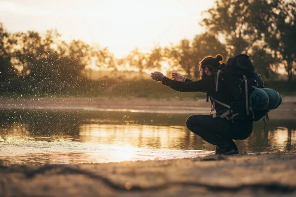 Mochileiro no lago brincando com água — Fotografia de Stock