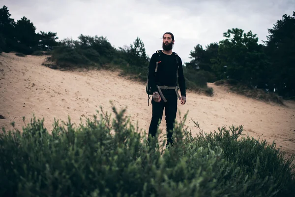 Человек с бородой стоит на песке — стоковое фото