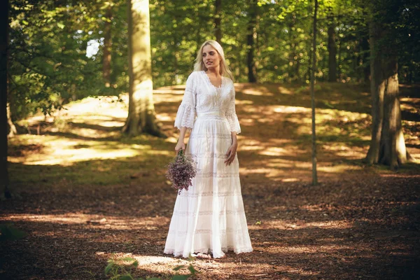 Mariée en robe blanche debout dans la forêt — Photo