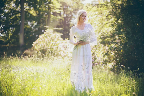 Hippie bruid houden van bloemen in bos — Stockfoto