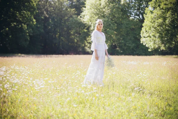 Novia con flores de pie en el campo — Foto de Stock