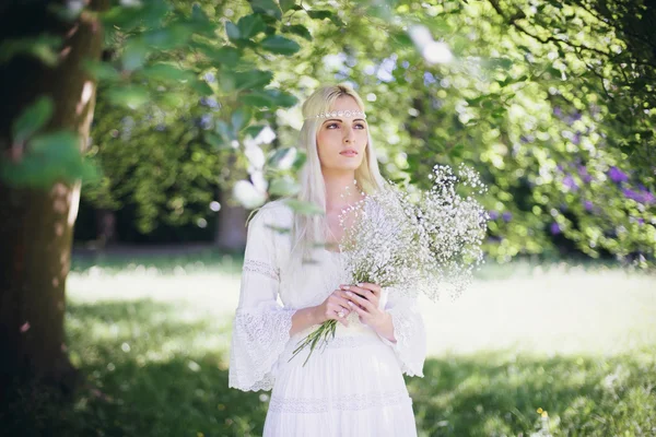 Mariée avec des fleurs debout sous l'arbre — Photo