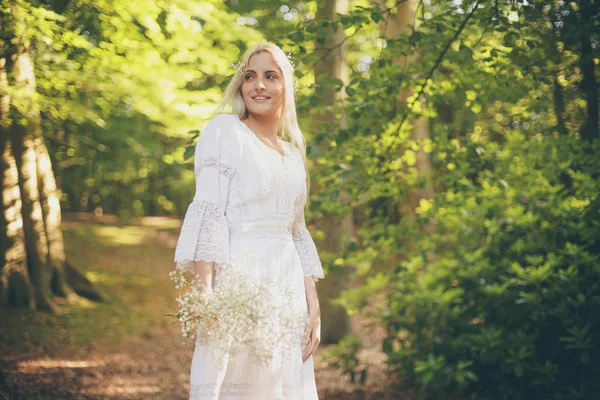 Lachende bruid in witte jurk in bos — Stockfoto