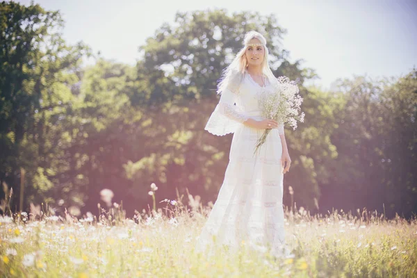 Mariée tenant des fleurs blanches dans le champ — Photo