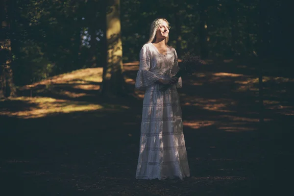 Noiva loira pegando luz solar na floresta — Fotografia de Stock