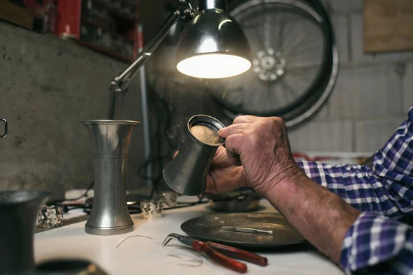 Man inspecting antique tin vase — Stock Photo, Image