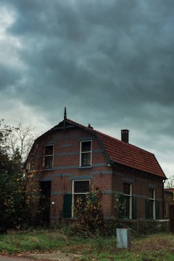 Sonbahar boyunca fırtınalı gökyüzü altında kırsalda bir ev.