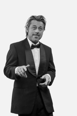 Beyaz duvarın önündeki smokinli komik adam. Siyah beyaz fotoğraf.