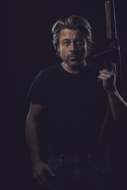 Koyu arkaplanda mavi tişörtlü sarışın adam..