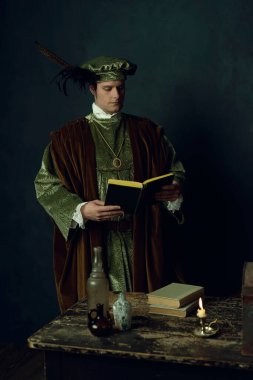 Elinde kitap olan bir Rönesans adamı üzerinde kitaplar, üç cam şişe ve bir şamdan olan bir masanın arkasında duruyor..