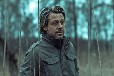 Sarışın, yeşil ceketli, uzun kamışların arasında akşam karanlığında doğa koruma alanında..