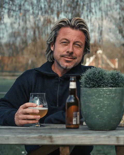 Blonder Mann Mit Bart Trinkt Bier Hinter Holztisch Hinterhof — Stockfoto