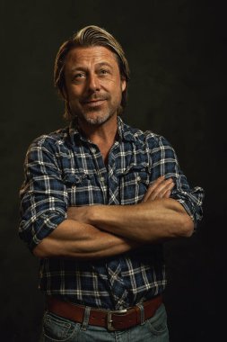 Mavi kareli gömlekli, sakallı, gülümseyen sarışın adam..