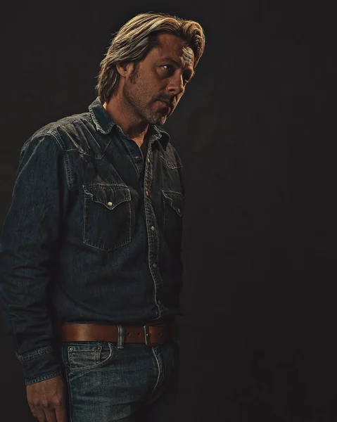 Man in jeans shirt and jeans with brown leather belt.