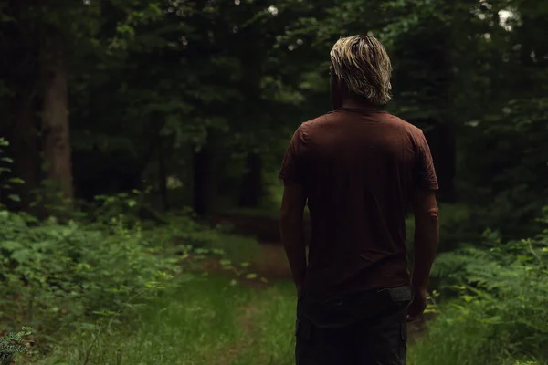 穿着棕色T恤的金发男人走在森林小路上 后视镜 — 图库照片