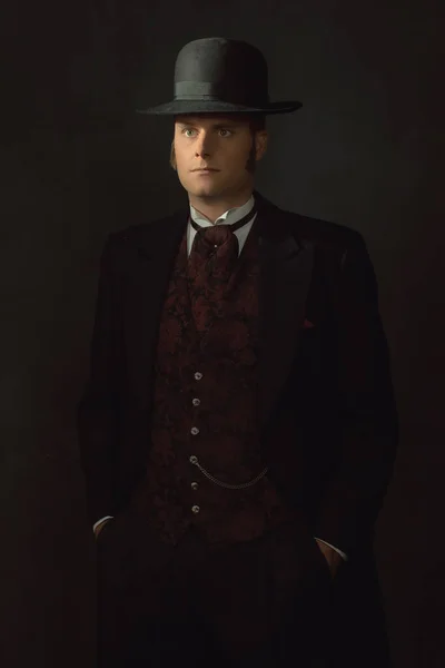 暗い灰色の壁の前でスタイリッシュなヴィンテージビクトリア朝の服装の若い男の影の肖像画 — ストック写真