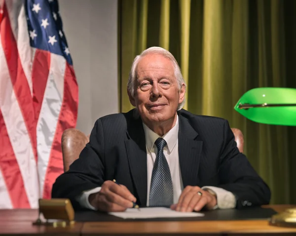 Gran jefe presidente escribiendo detrás del escritorio con la bandera americana en el —  Fotos de Stock