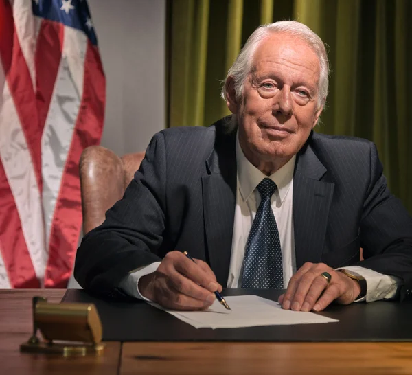 Grande chefe presidente escrevendo atrás da mesa com bandeira americana no — Fotografia de Stock