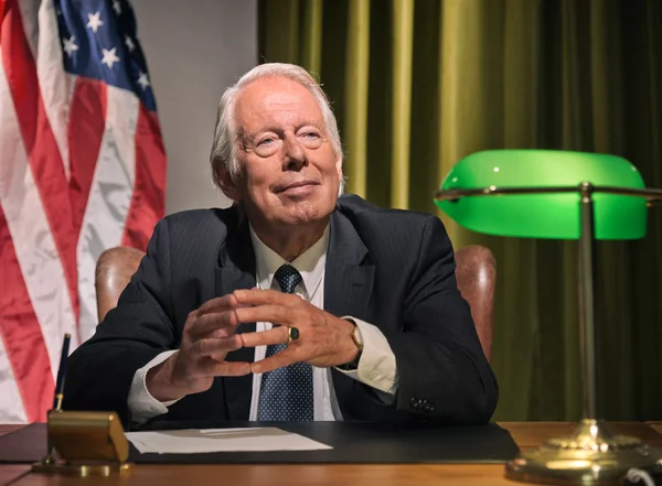 Grande chefe presidente sentado atrás da mesa com bandeira americana no — Fotografia de Stock