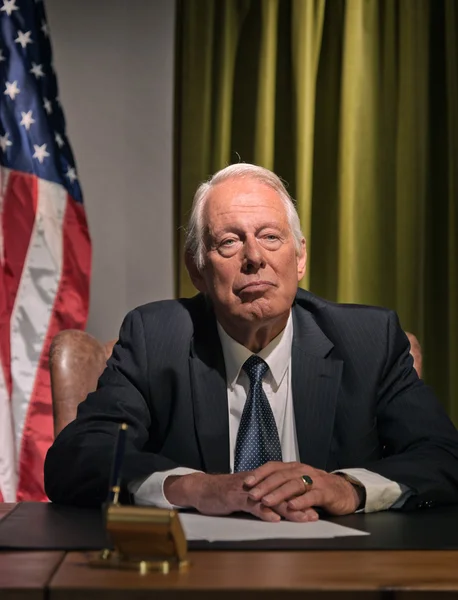 Grande chefe presidente sentado atrás da mesa com bandeira americana no — Fotografia de Stock