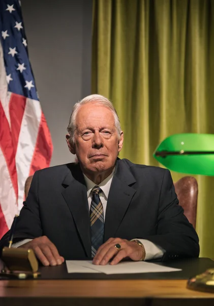 Grande chefe presidente sentado atrás da mesa com bandeira americana no — Fotografia de Stock