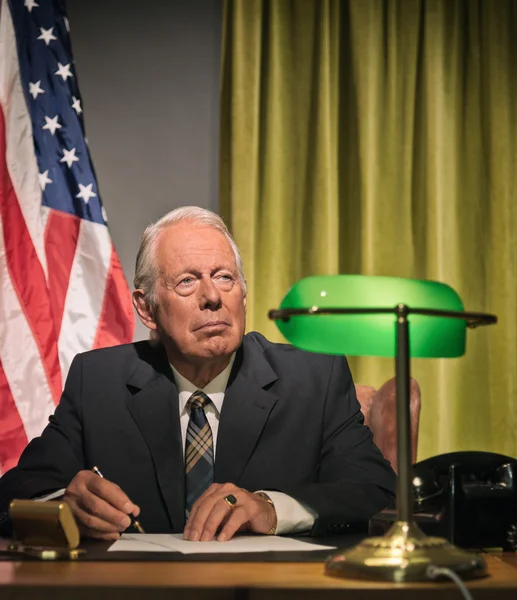Grande chefe presidente escrevendo atrás da mesa com bandeira americana no — Fotografia de Stock