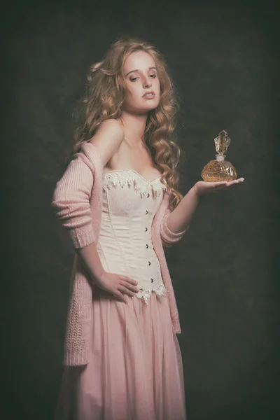 Vintage módní žena drží staré parfémy láhev. na sobě růžové c — Stock fotografie