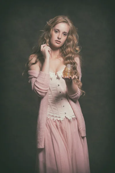 Mulher de moda vintage segurando garrafa de perfume velho. Vestindo rosa c — Fotografia de Stock