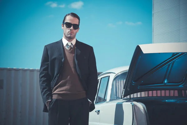 Retro fifties mafia fashion man standing next to open trunk of v — Stock Photo, Image