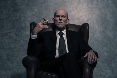Cigar smoking senior businessman with gray beard wearing dark su clipart